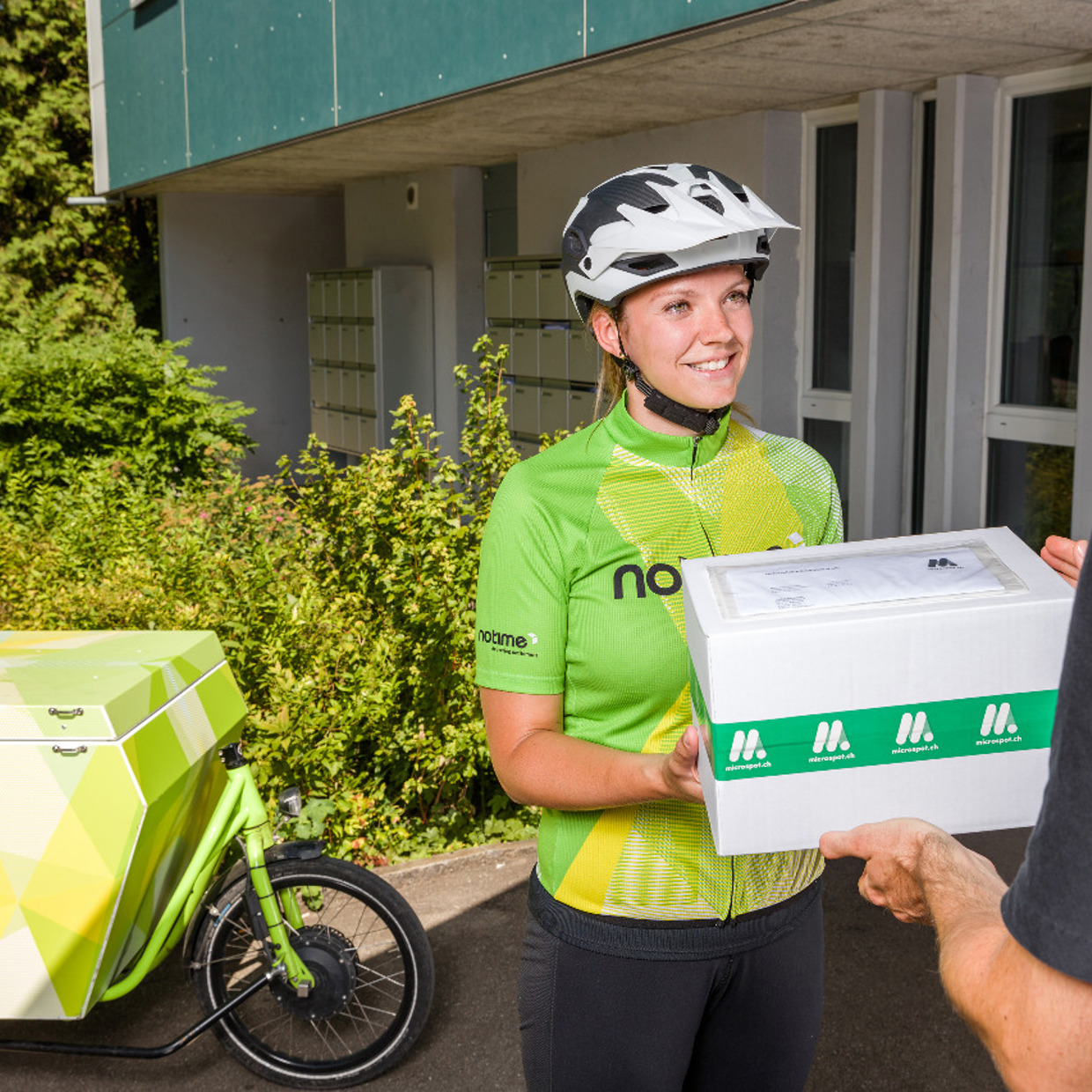 notime Velokurierin übergibt ein Paket an einen zufriedenen Kunde